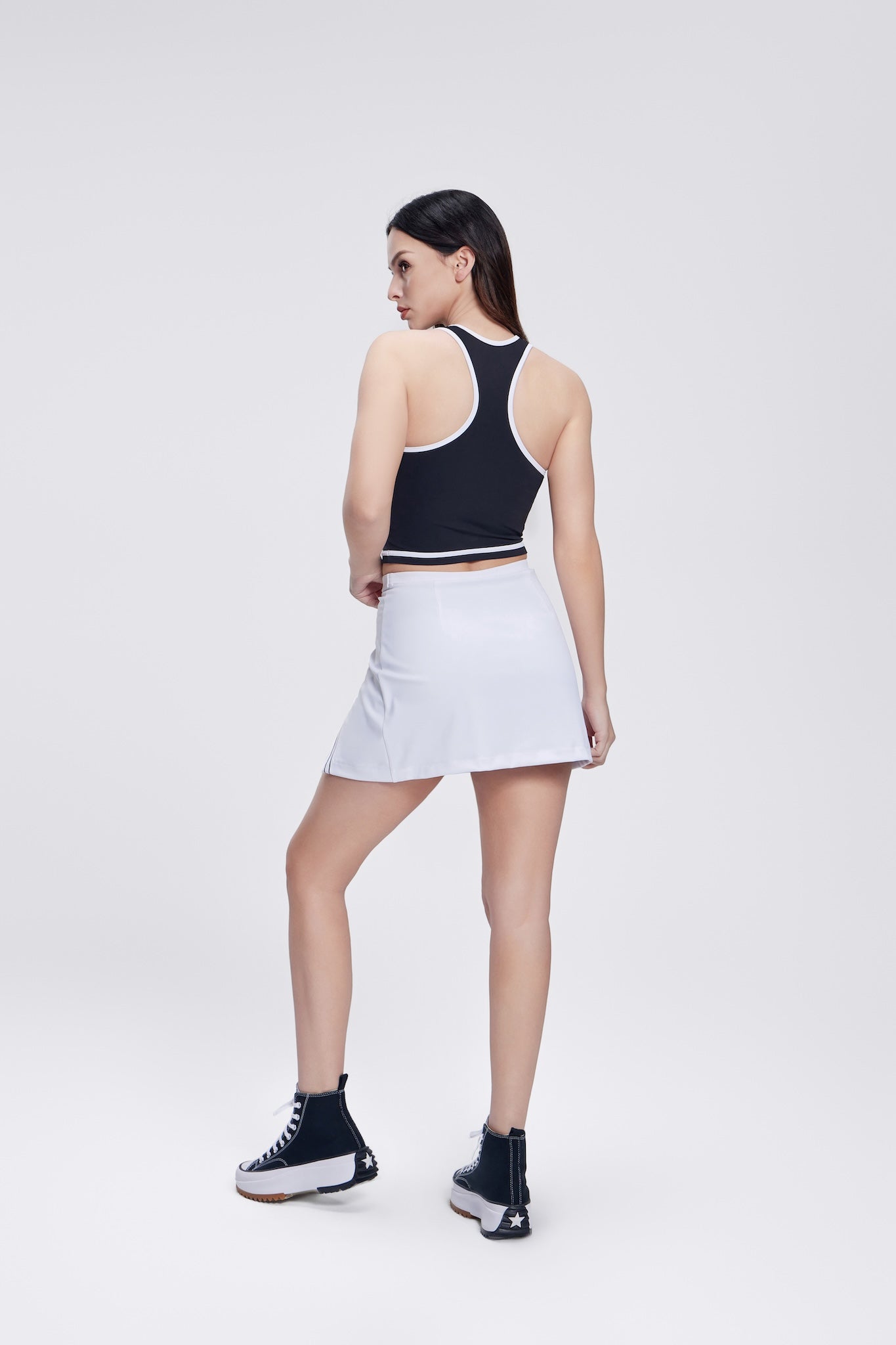 Chic Side Split Tennis Skirt for women in a crisp white color. Features a high waistband, side splits for enhanced movement, and built-in shorts for comfort and coverage, perfect for tennis and active wear.